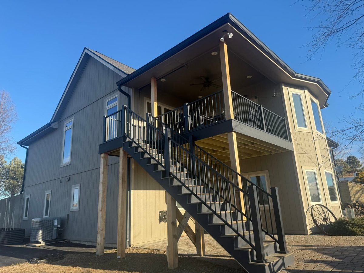 Elevated covered deck with black railing and custom exterior stairs